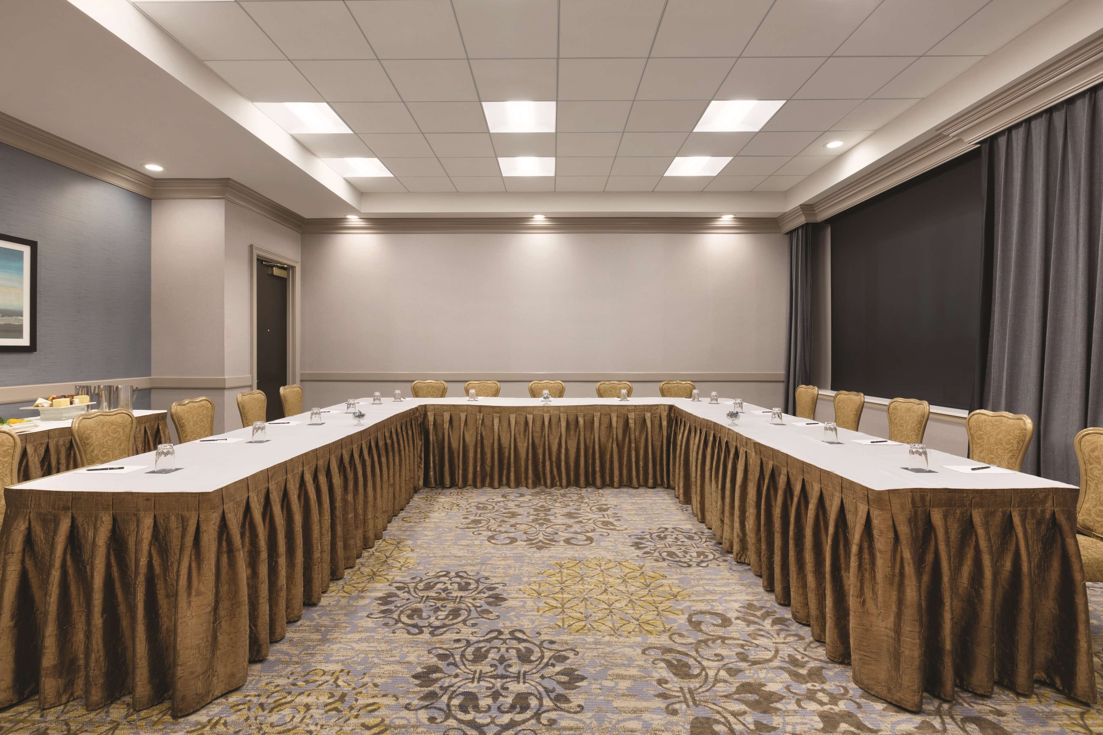 A conference room with a long table, chairs, and a carpeted floor.