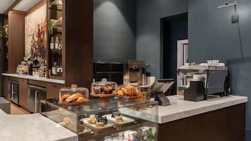 A breakfast bar with pastries, beverages, and a coffee machine.