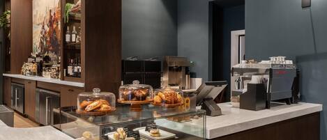 Una barra de desayuno con pasteles, bebidas y una máquina de café.