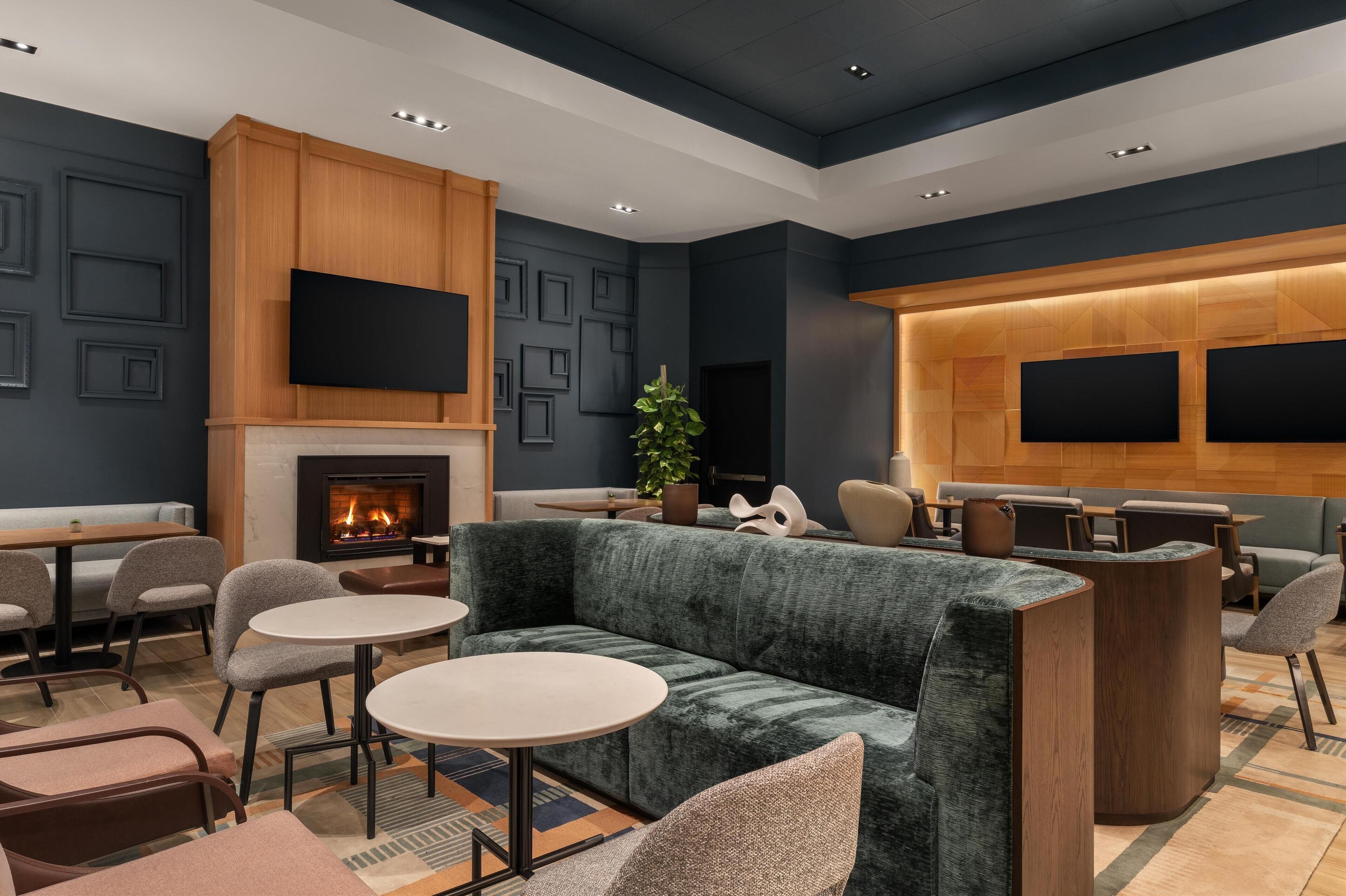 A modern lounge area with a fireplace, seating arrangements, and a large wall-mounted TV screen.