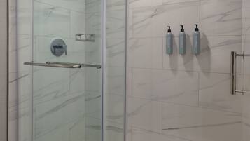 A glass-enclosed shower with a glass door, a handrail, and a showerhead.