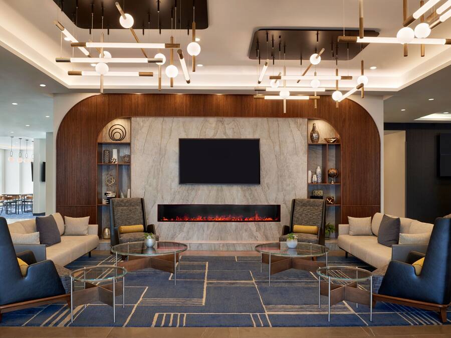 A modern lobby with a large TV, a fireplace, and comfortable seating areas.