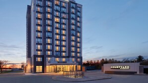 Un hotel de varias plantas con un diseño moderno, que destaca por una entrada imponente con fachada de vidrio y un letrero que dice "Courtyard by Marriott".