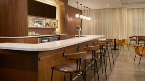 Un área de bar moderna con una barra curva, taburetes y un enfriador de vino.