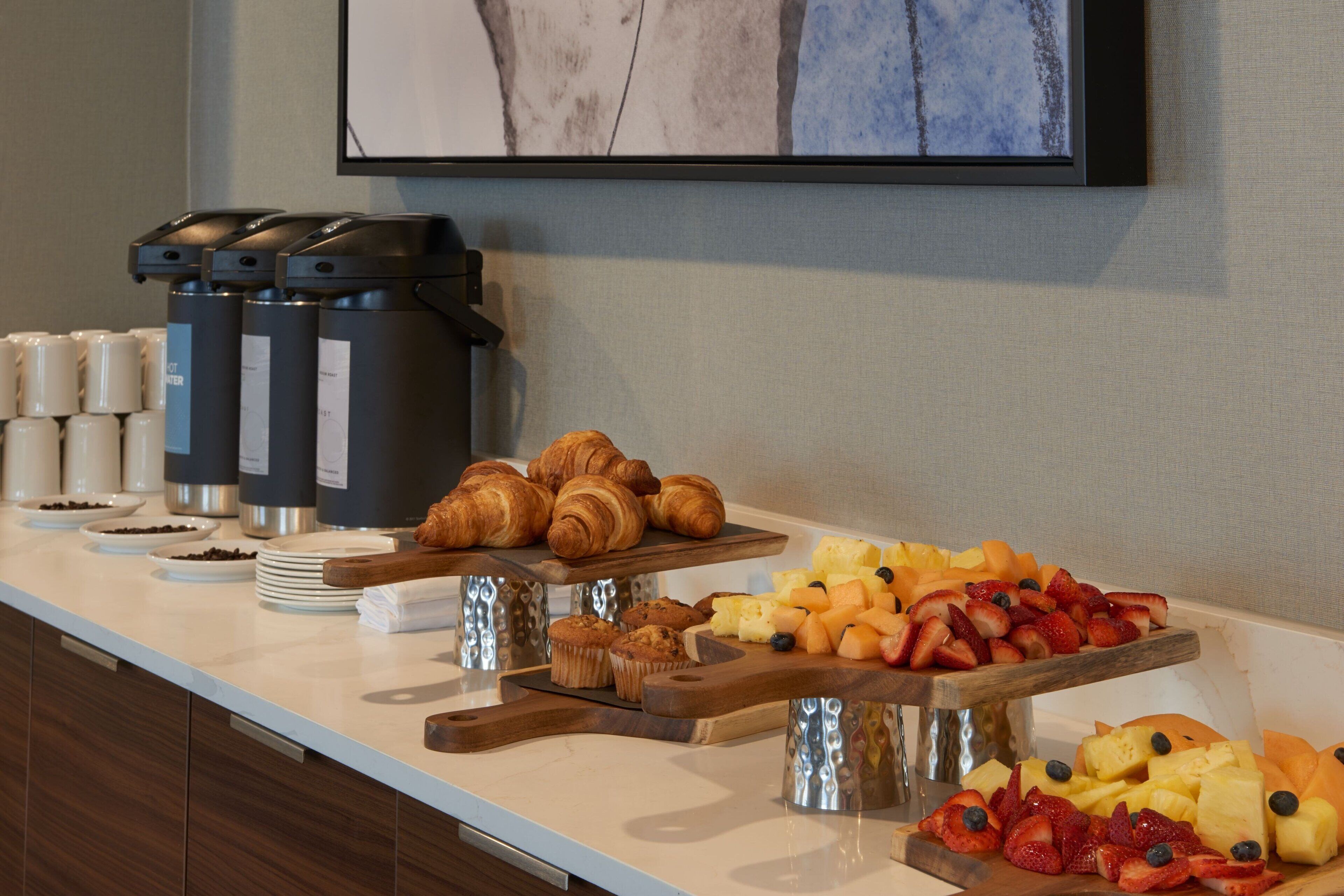 A breakfast buffet with croissants, muffins, and a variety of fruits.