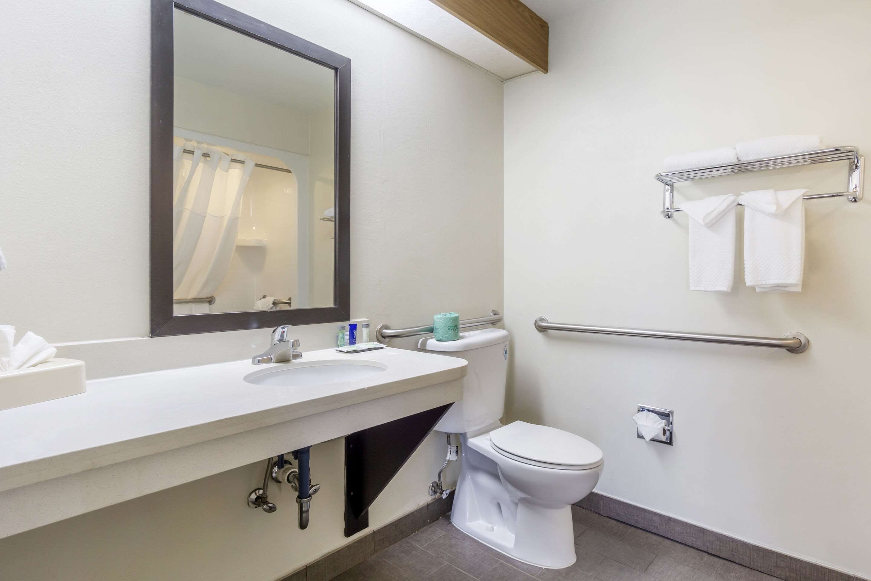 Een moderne badkamer met een wastafel, spiegel, toilet en handdoekrek.
