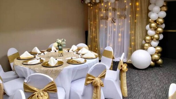 A round table set for a formal event with white and gold decorations, including balloons and a draped curtain. - Sleep Inn - SeaTac Airport (SeaTac)