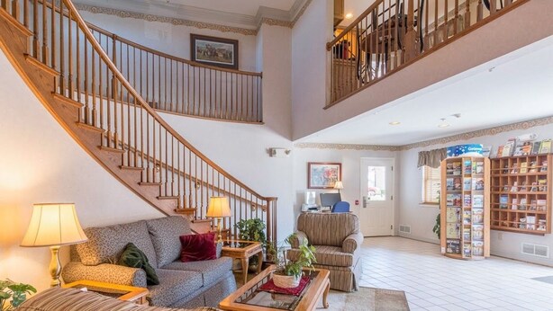 A spacious living area with a staircase, a sofa set, a coffee table, and a bookshelf. - Inn at Cemetery Hill (Gettysburg)