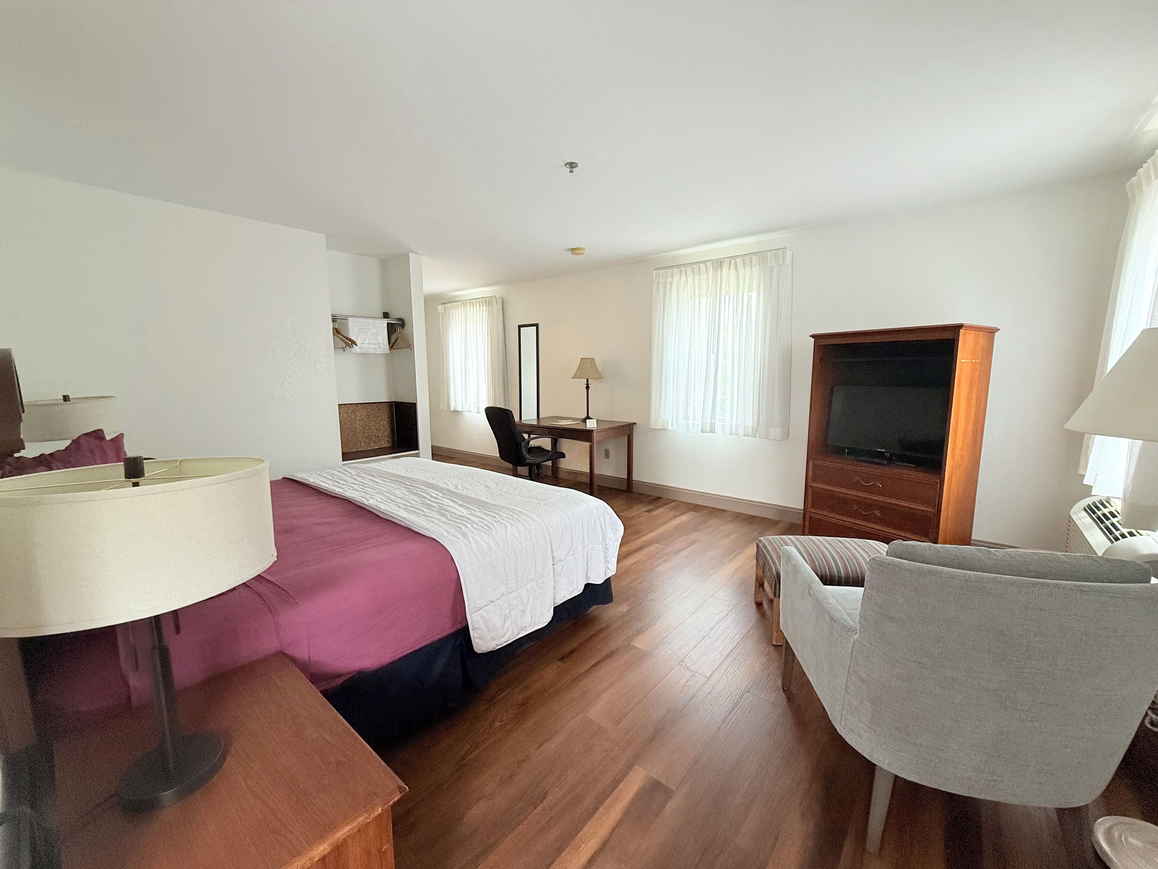Ein Hotelzimmer mit Bett, Schreibtisch, Stuhl, Fernseher und Lampe.