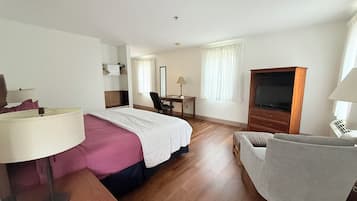 Ein Hotelzimmer mit Bett, Schreibtisch, Stuhl, Fernseher und Lampe.