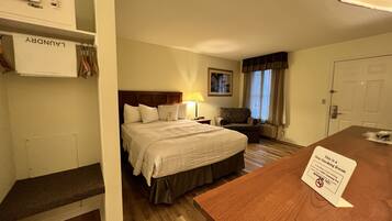 A hotel room with a bed, a desk, a chair, a lamp, and a sign indicating it is a non-smoking room.