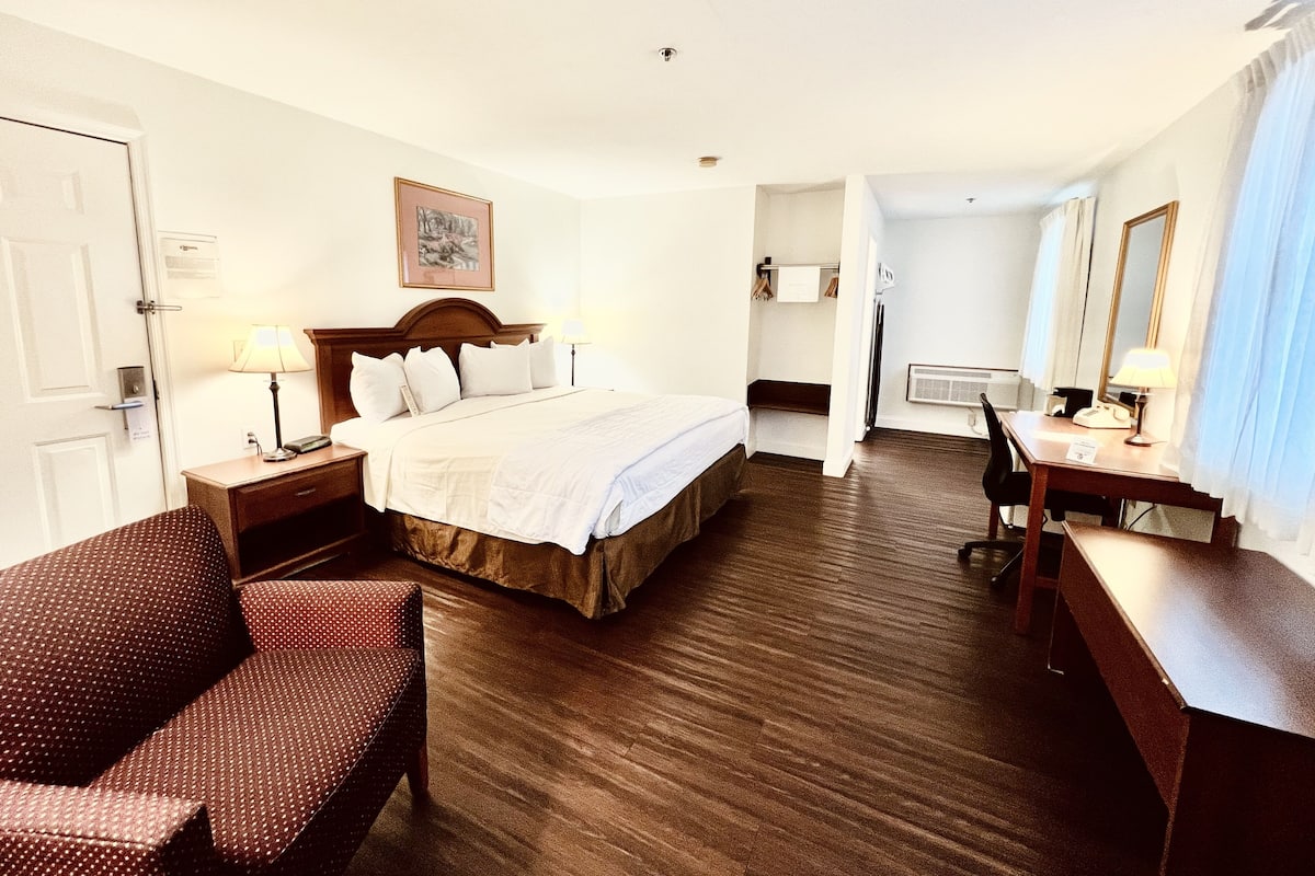 A hotel room with a bed, a desk, a chair, and a bathroom visible through an open door.