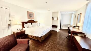 Habitación de hotel con una cama, un escritorio, una silla y un baño visible a través de una puerta abierta.