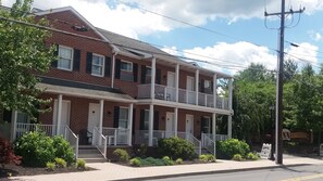 A two-story brick building with a balcony on the second floor, a front porch, and a sign for a cemetery.