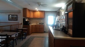 A kitchen with wooden cabinets, a dining area with a table and chairs, a refrigerator, and a window providing natural light.