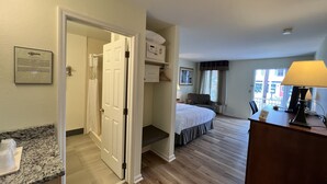 A hotel room with a bed, a desk with a lamp, a chair, and a window with curtains. - Inn at Cemetery Hill (Gettysburg)