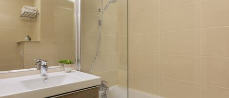 A bathroom with a sink, mirror, and shower.