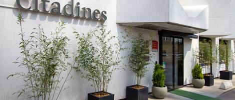 Un immeuble portant l’enseigne « Citadines », avec plusieurs plantes en pot devant l’entrée.