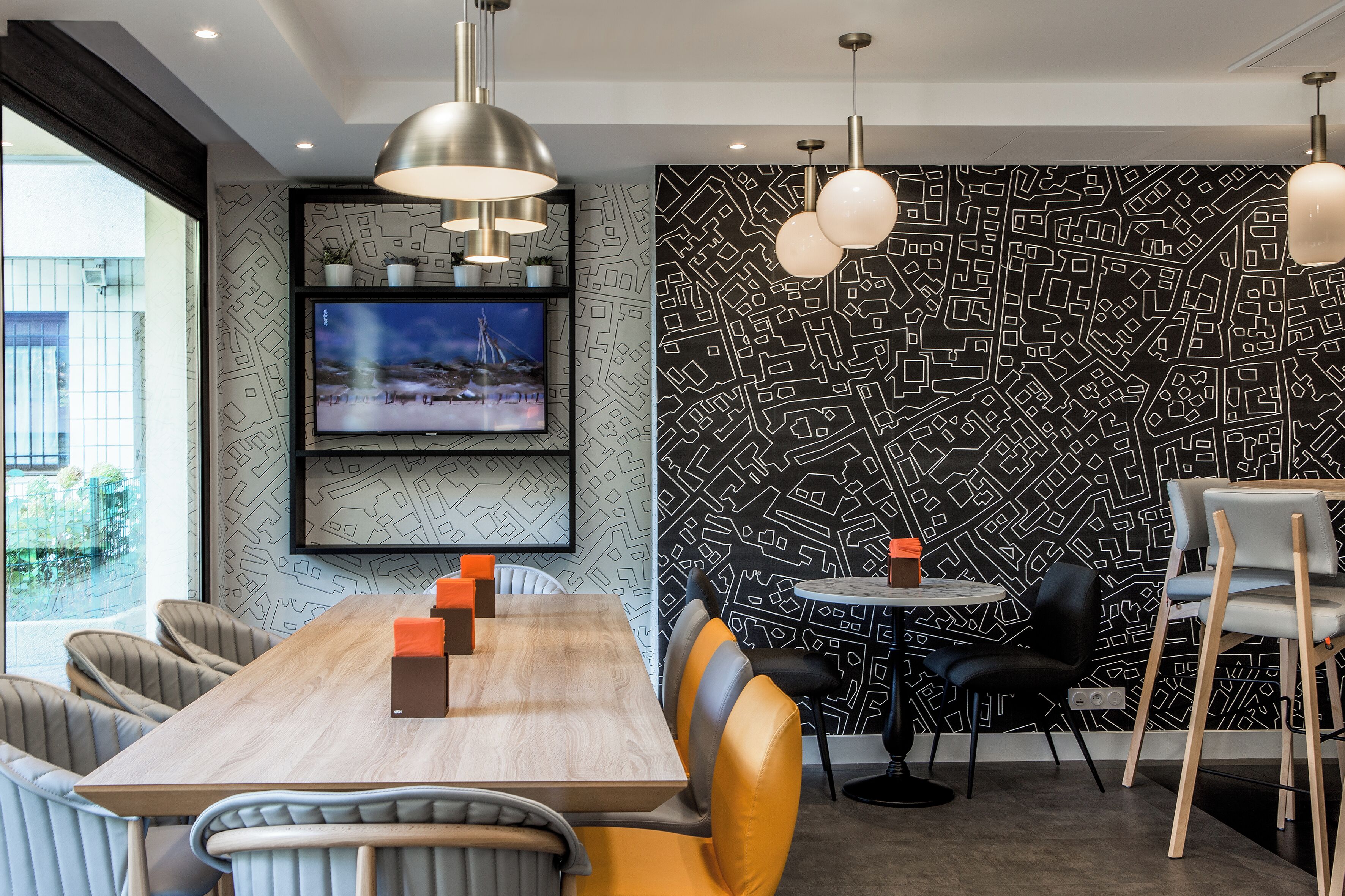 A modern dining area with a wooden table, chairs, and pendant lighting.