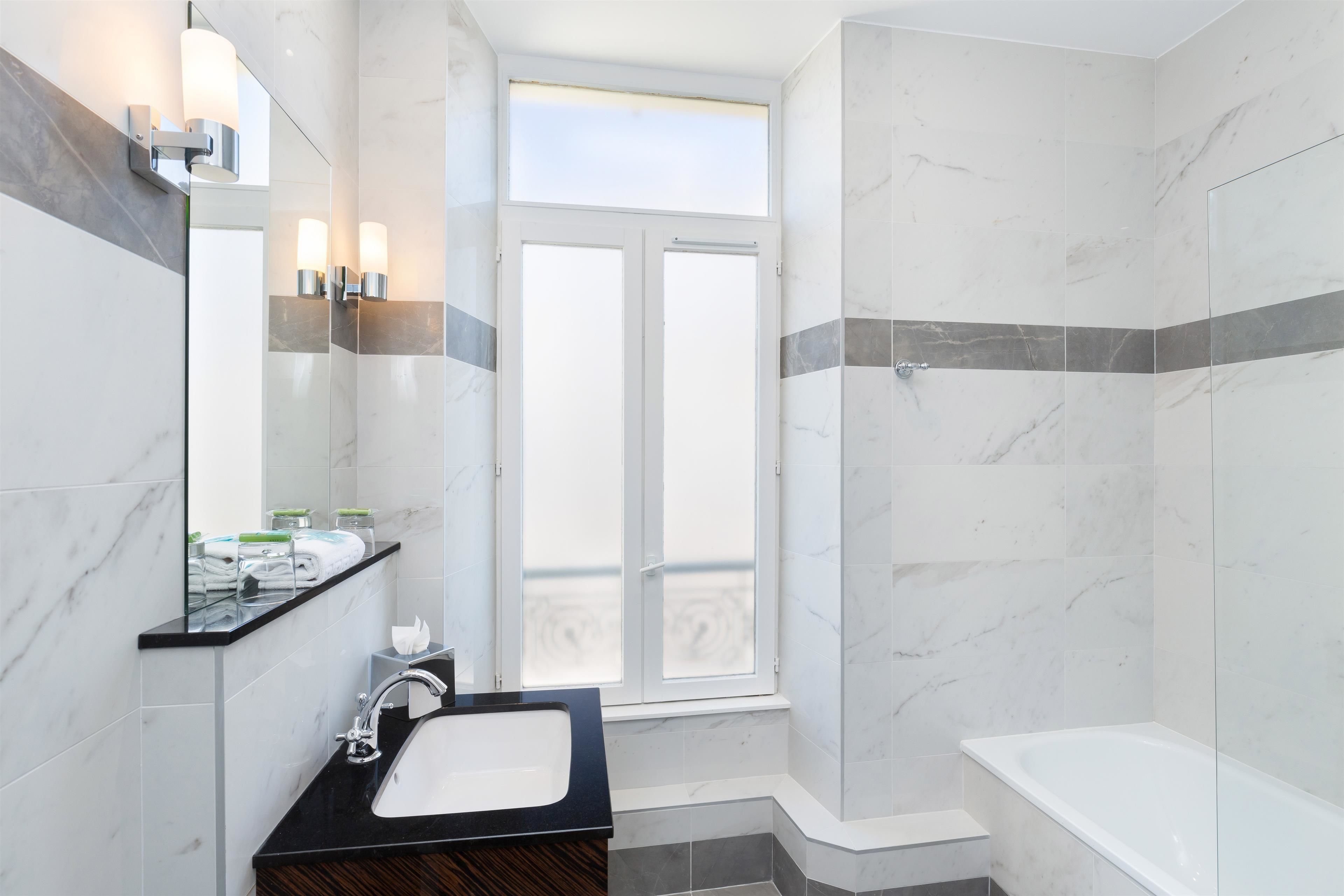 A modern bathroom with a large mirror, a sink, and a shower.