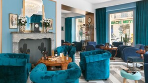Un salon moderne avec des canapés recouverts d’un tissu turquoise, une table basse en bois et un lustre.