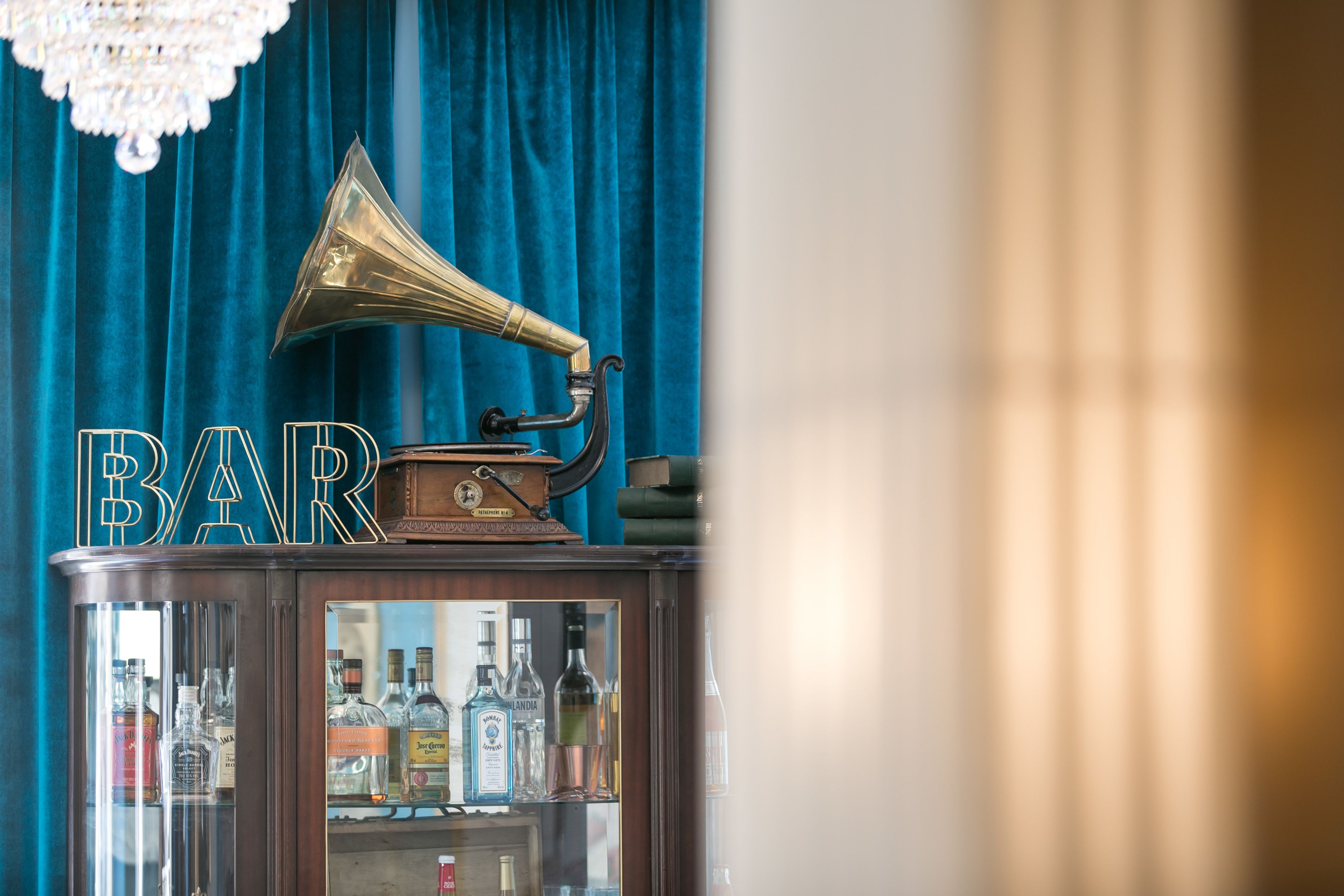 Ein Vintage-Grammophon auf einer Holzkabine mit einer Glasvitrine für Spirituosenflaschen.