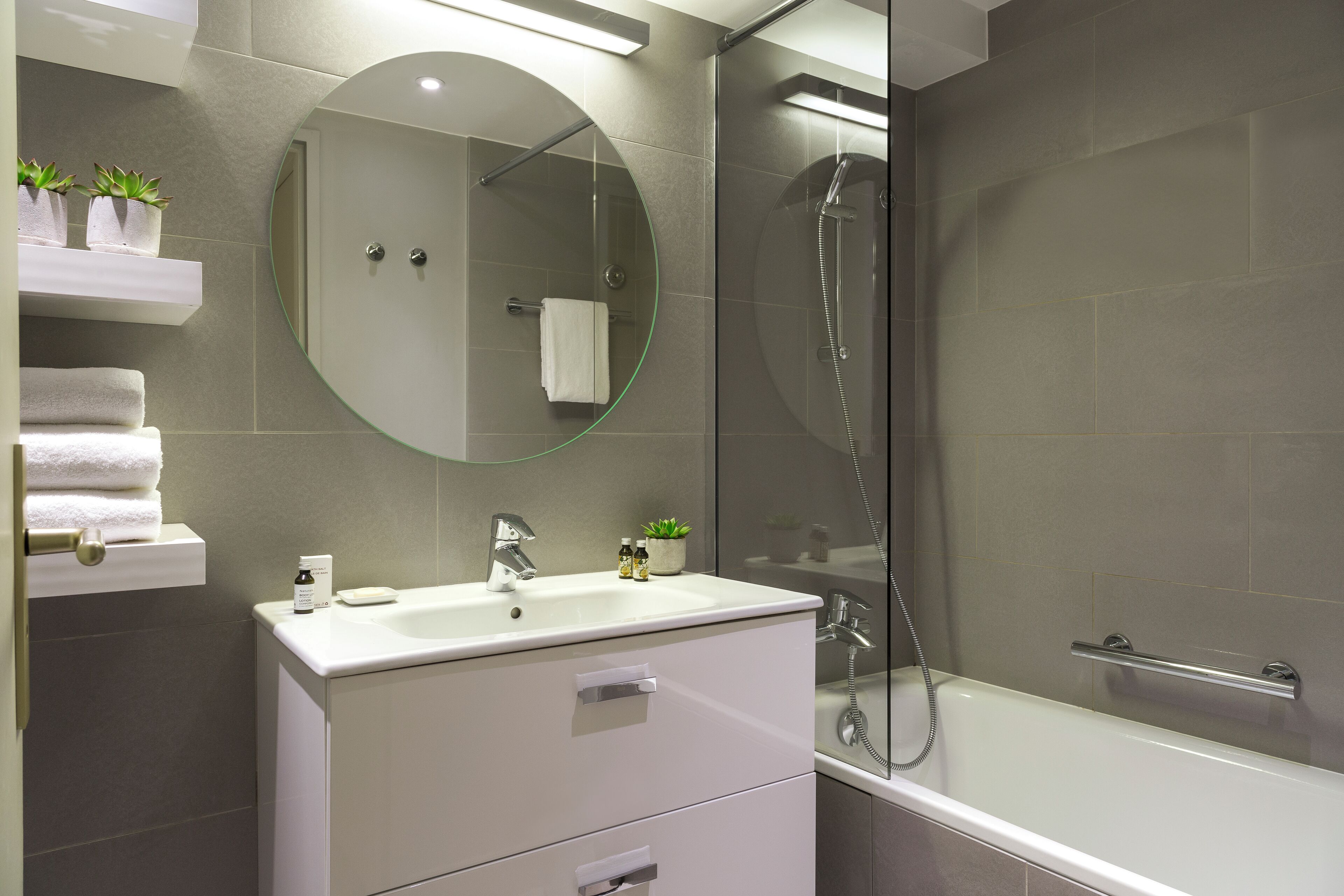 A modern bathroom with a glass-enclosed shower, a white sink, and a mirror above it.
