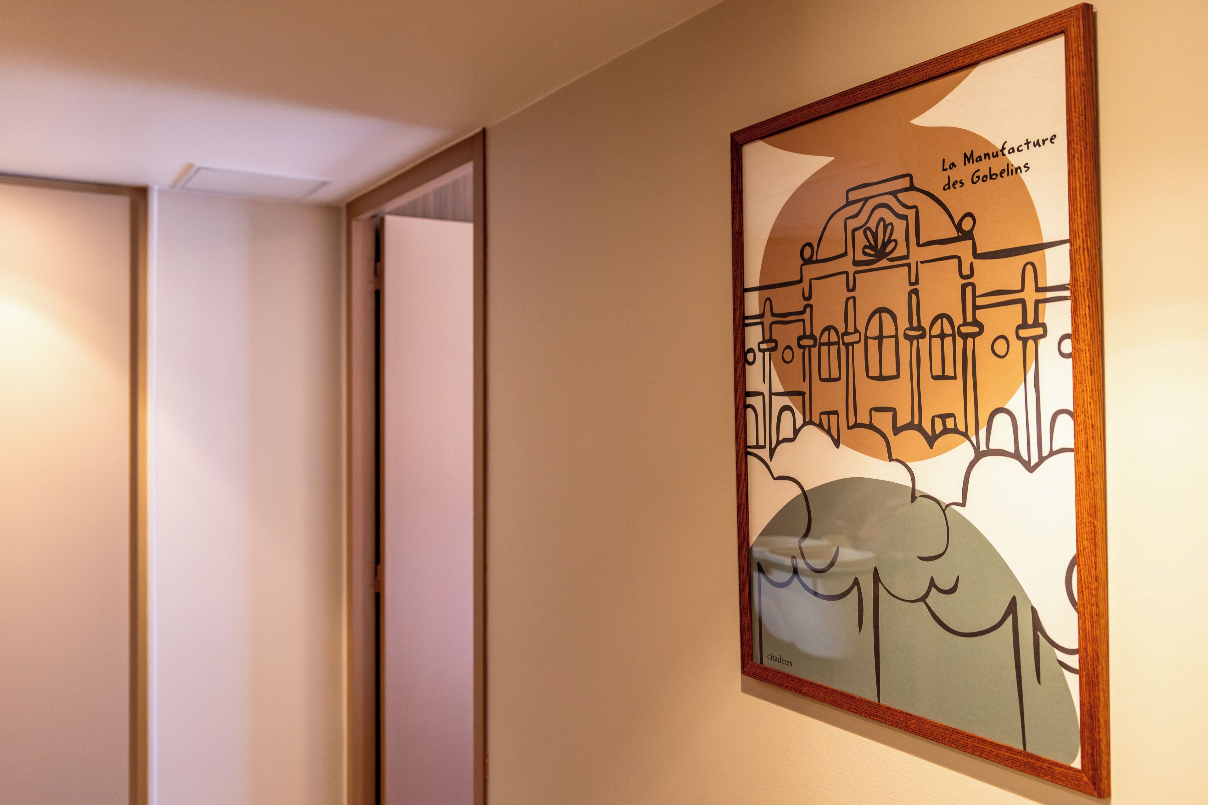 A framed artwork depicting a building with the text 'La Manufacture des Gobelins' and 'citadines' on the wall.