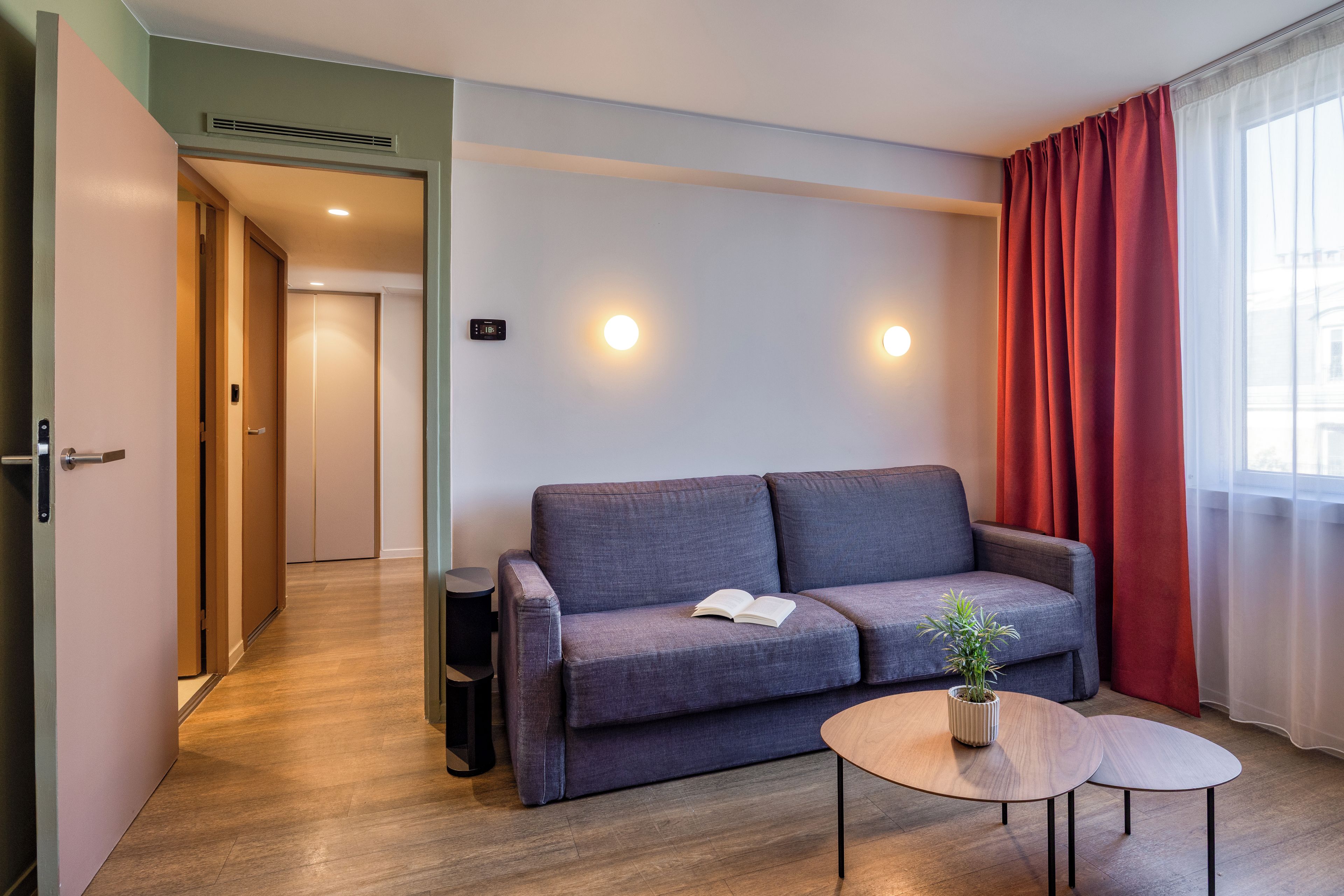 A modern room with a grey sofa, a small round table, and a potted plant.