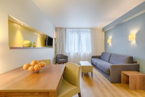Un soggiorno moderno con un tavolo da pranzo in legno, un divano, una TV a parete e una finestra con tende.