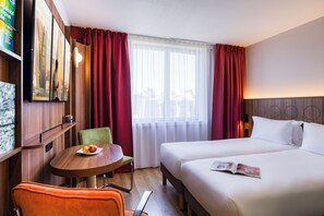 A hotel room with a bed, a chair, a table with fruit, a TV, and curtains. - Citadines Place d’Italie Paris (Paris)