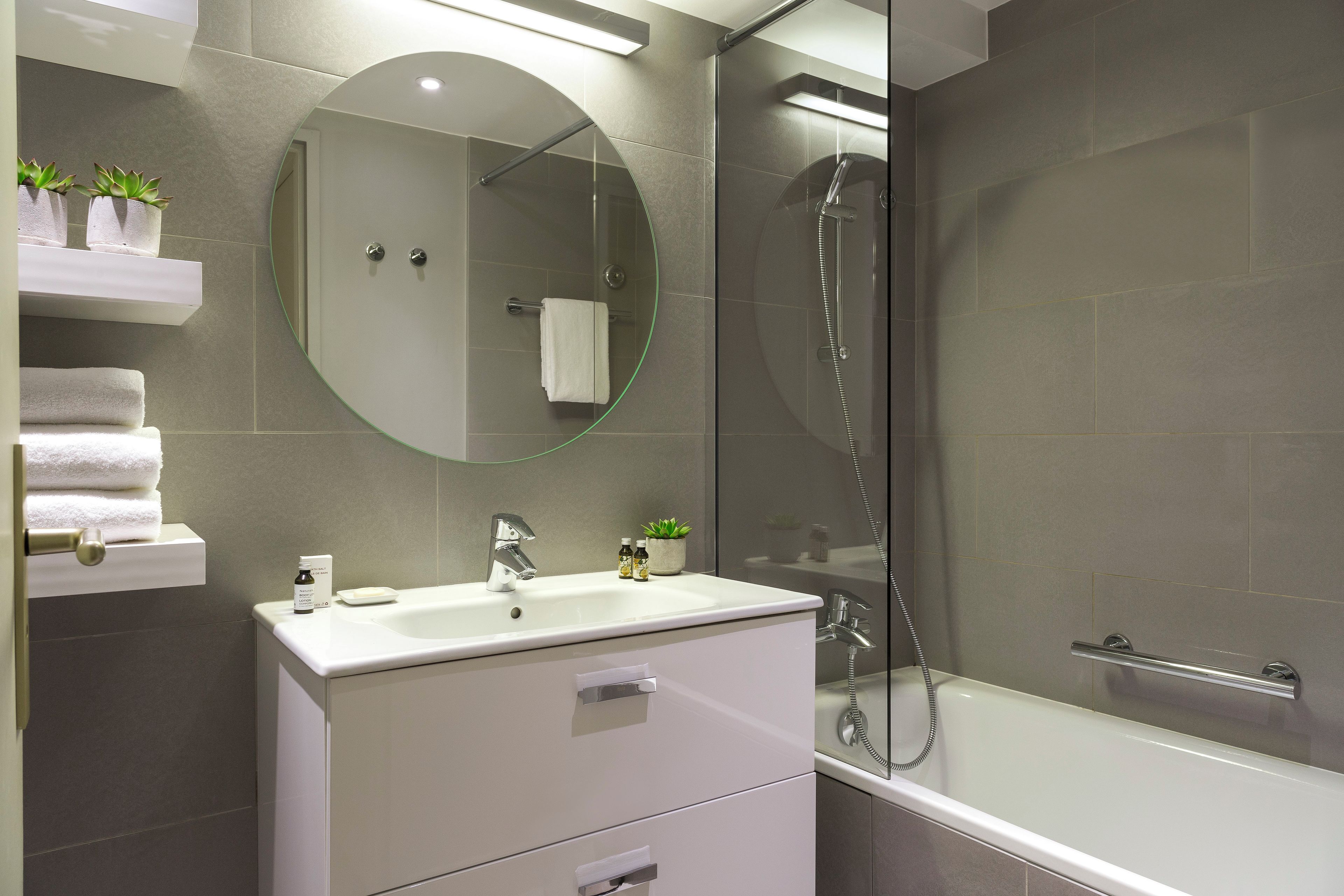 A modern bathroom with a glass-enclosed shower, a white vanity with a mirror, and a towel rack.