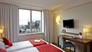 A hotel room with two beds, a desk, a chair, a TV, and a window with a city view. - Citadines Place d’Italie Paris (Paris)