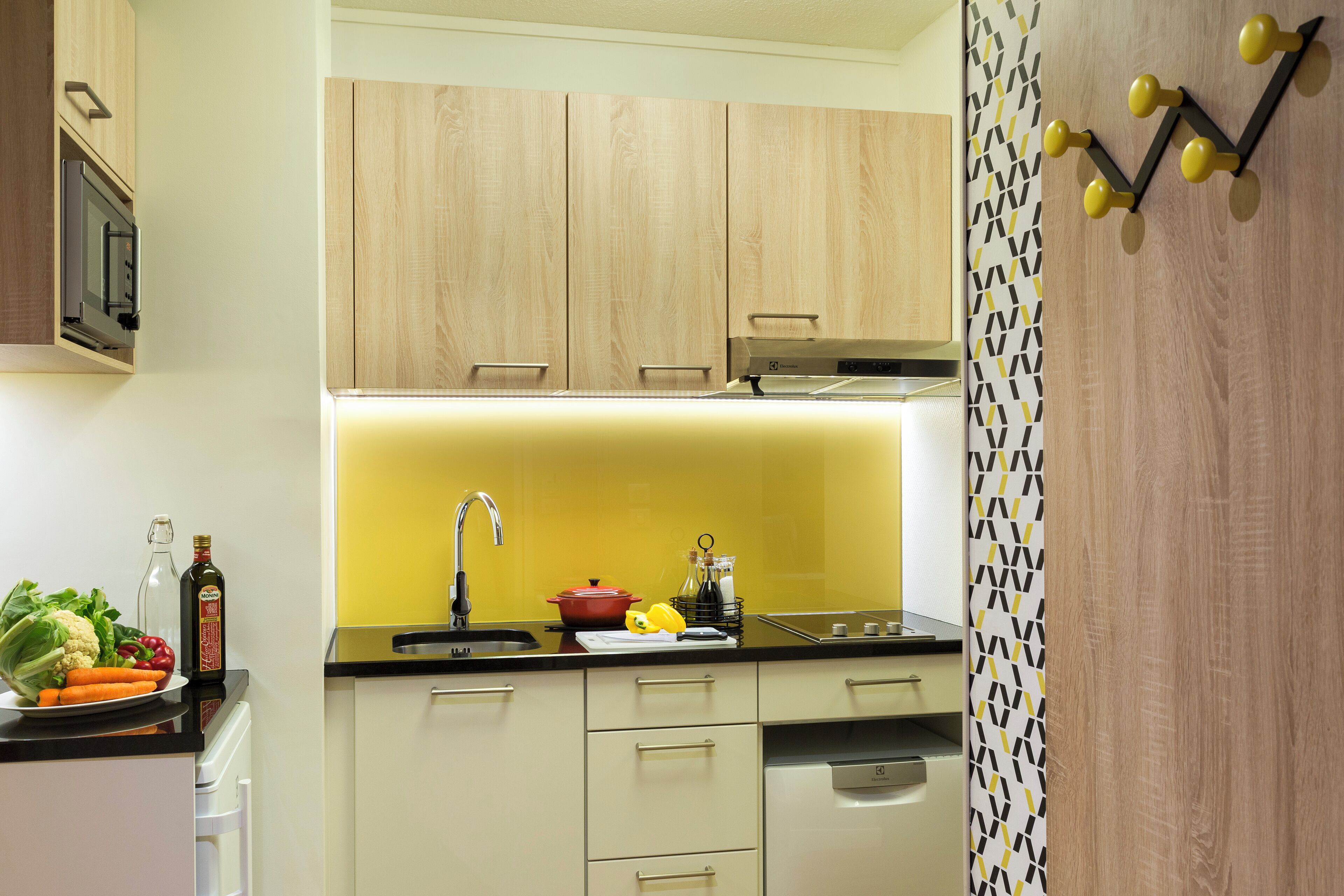 A kitchen with wooden cabinets, a black countertop, and a yellow backsplash.