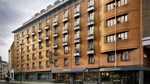 A multi-story building with a brick facade, multiple balconies, and storefronts including 'CITADINES'. - Citadines Barbican London (London)