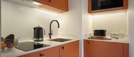 A modern kitchen with a black microwave, a kettle, and a sink.