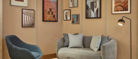 A modern living room with a grey sofa, a blue armchair, and a coffee table with books.