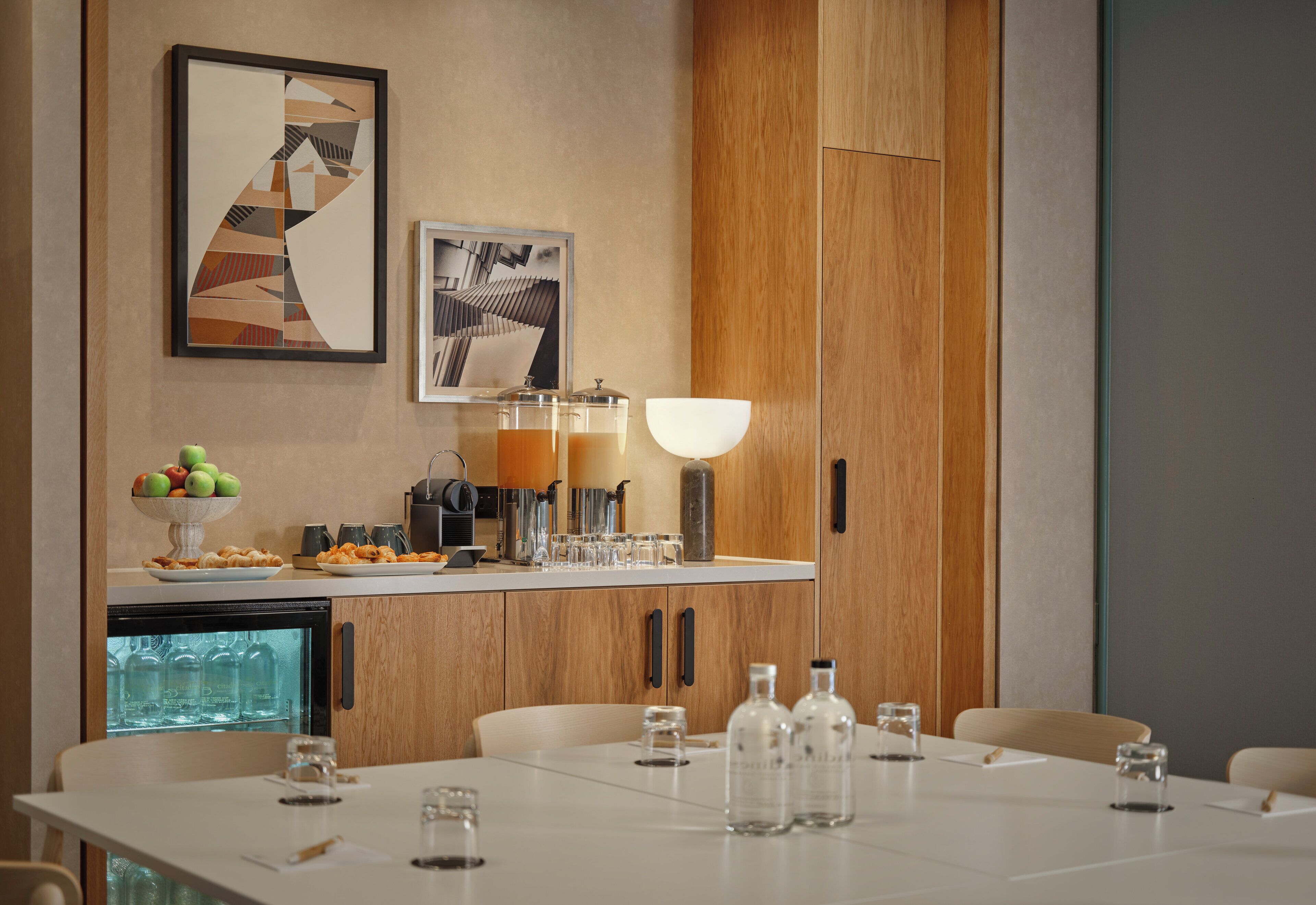 A modern kitchen with wooden cabinets, a refrigerator, and a dining area with a table set for four.