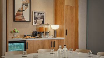 A modern kitchen with wooden cabinets, a refrigerator, and a dining area with a table set for four.