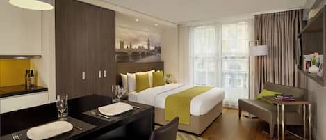 Habitación de hotel con cama, escritorio con silla, televisor y ventana con cortinas.