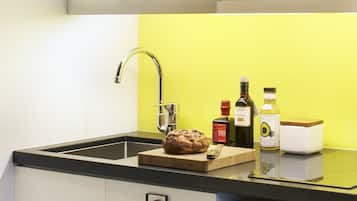 A kitchen with a microwave, a sink with a faucet, and a bread loaf on the counter.