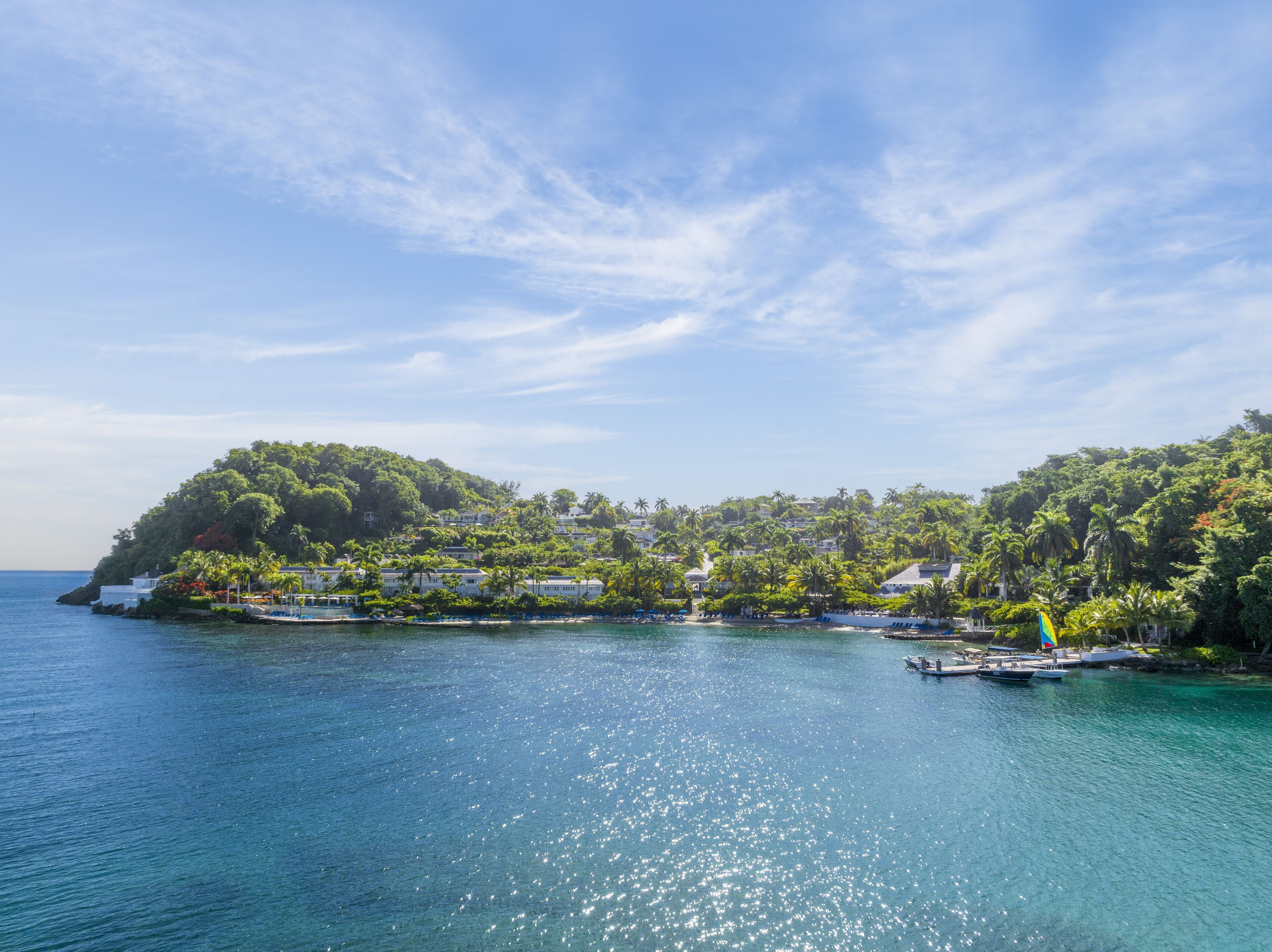 A coastal view with a small island, clear blue water, and a few boats.