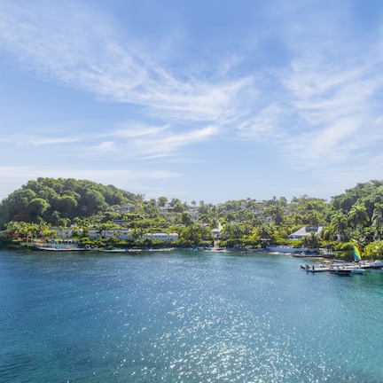 A coastal view with a small island, clear blue water, and a few boats.