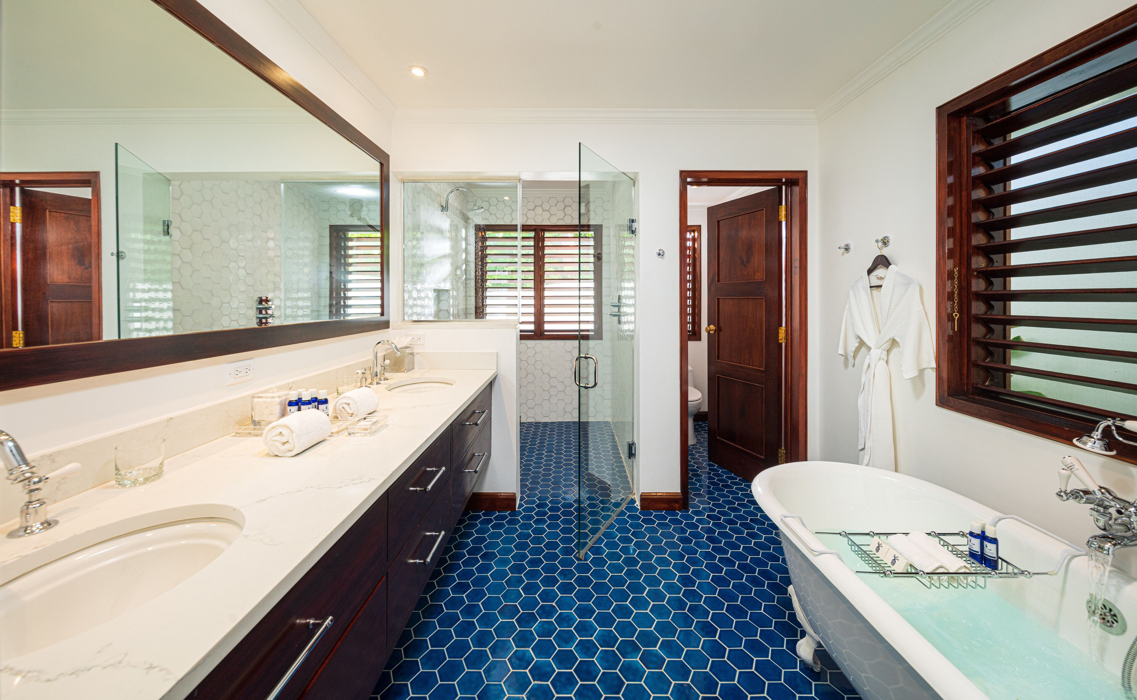 Un baño moderno con un espejo grande, dos lavamanos, una ducha y una bañera.