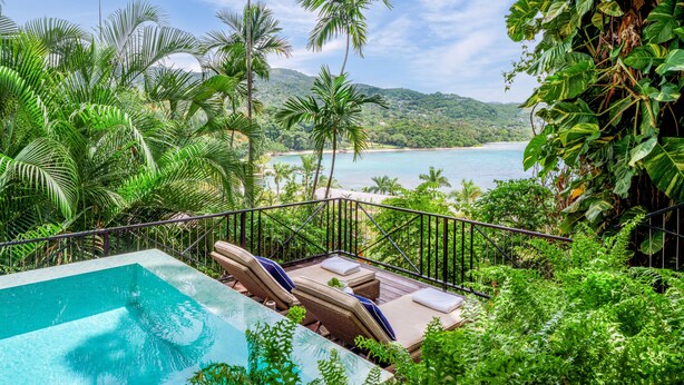 A poolside area with lounge chairs and a view of a beach and ocean. - Round Hill Hotel And Villas (Montego Bay)