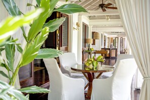A dining area with a round table, white chairs, and a ceiling fan.