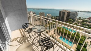 A balcony with a glass table and chairs, overlooking a swimming pool and a bridge. - Fortune House Hotel Suites (Miami)