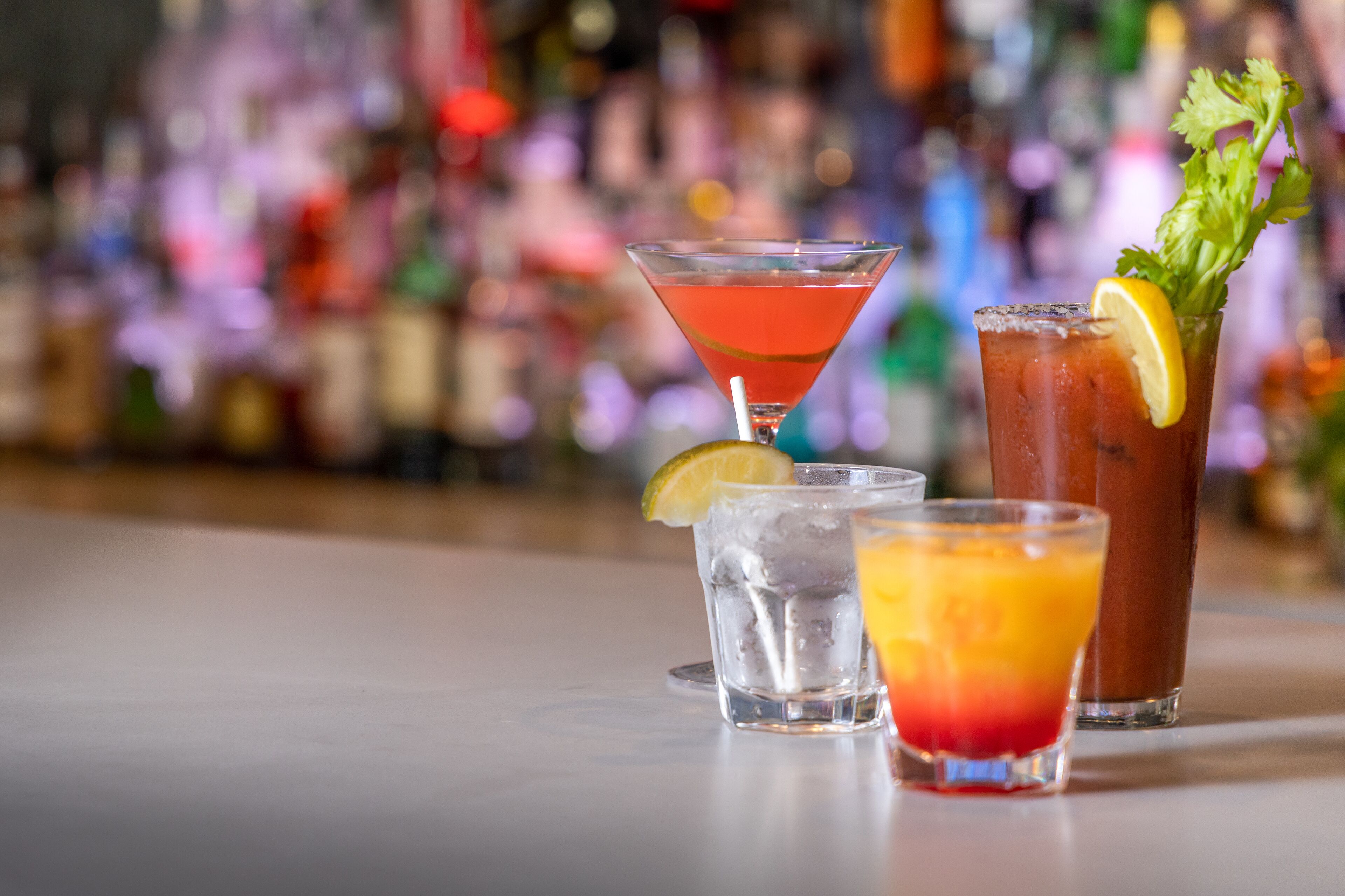 Un bar proposant une variété de boissons, notamment des martinis, des Bloody Mary et un cocktail agrémenté d’une tranche de citron.