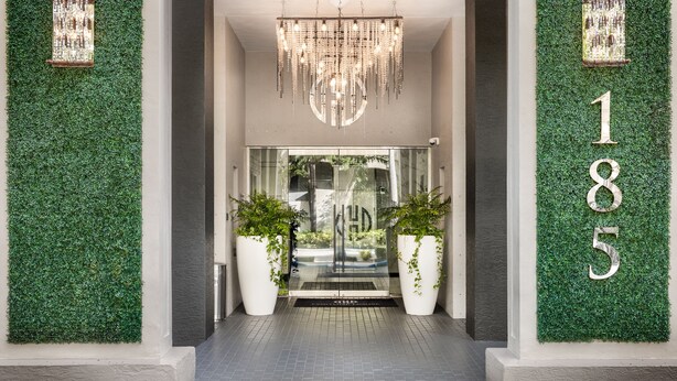 A modern hotel entrance with a green wall, a chandelier, and a glass door. - Fortune House Hotel Suites (Miami)