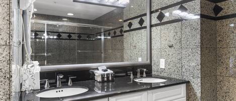 Une salle de bain moderne avec deux lavabos, un grand miroir et un sèche-cheveux.